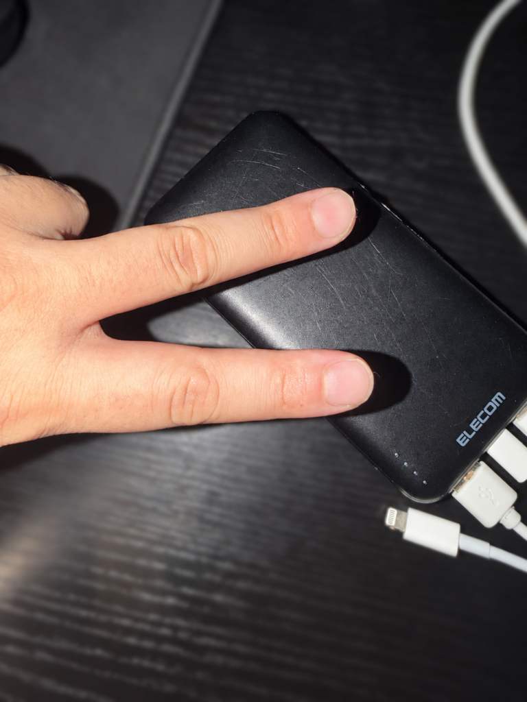 ピースサインの手と比べたエレコムのモバイルバッテリーの大きさ